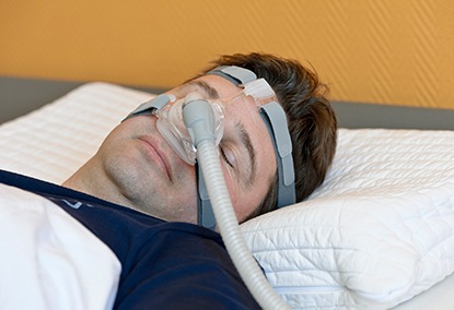 Man asleep using combined CPAP and oral appliance therapy for sleep apnea
