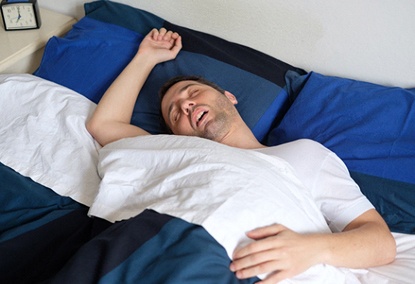 Man with sleep apnea snoring and sprawled out in bed