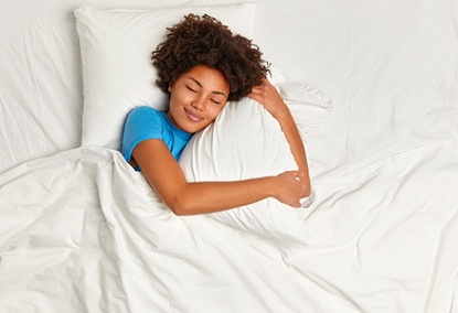 Young woman hugging her pillow and sleeping peacefully