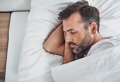 Man sleeping soundly with sleep apnea oral appliance