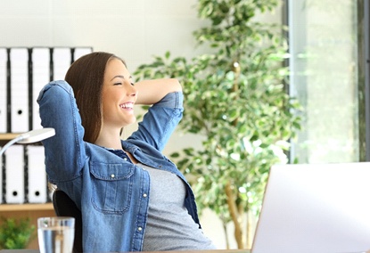 Woman sitting at a computer feeling refreshed. 