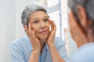Woman with sleep apnea looking in mirror, noticing signs of aging