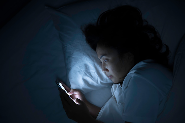 restless woman on phone in bed at night